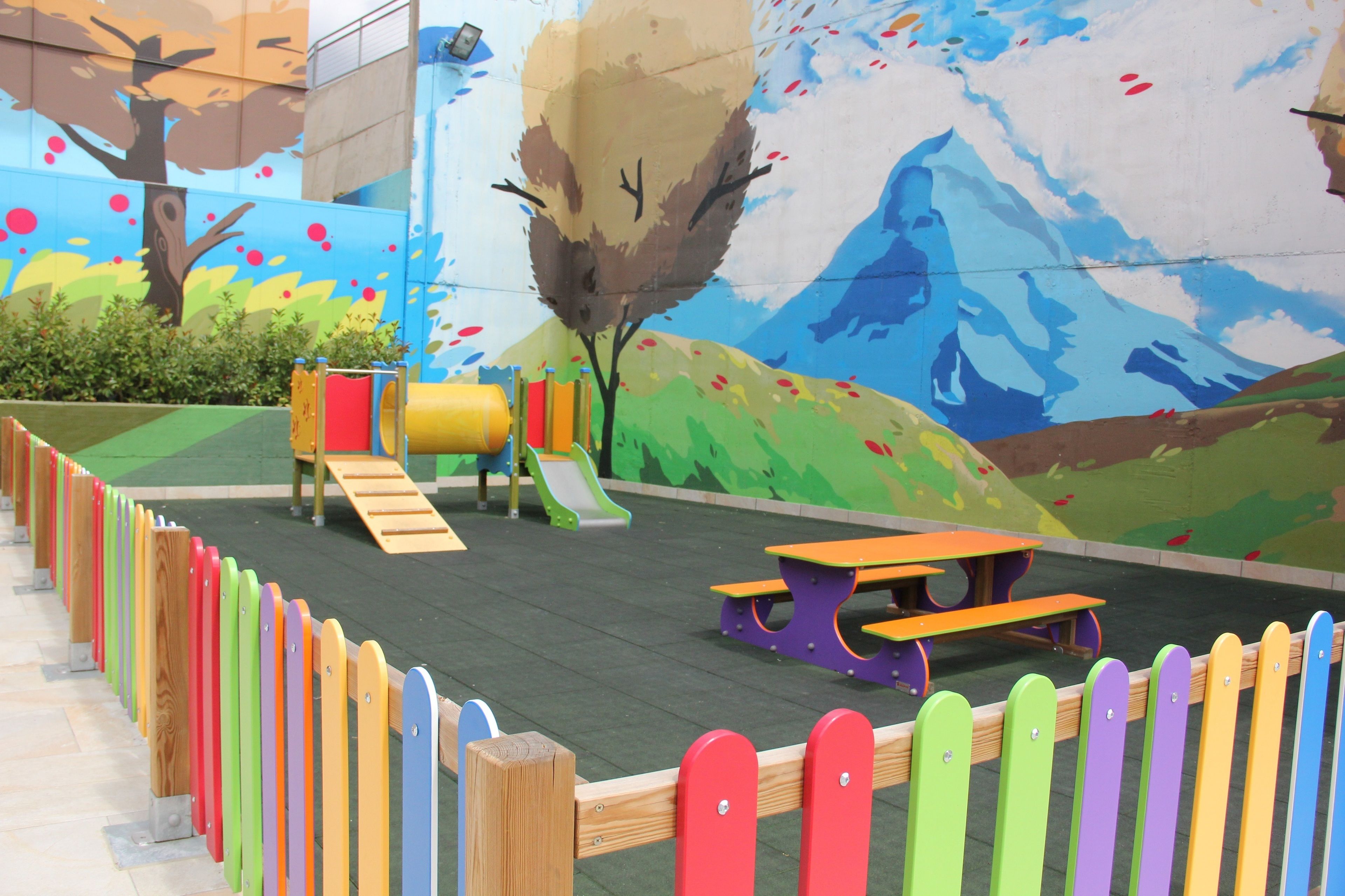 Un parque infantil con tobogán, estructuras de escalada y mesas de picnic.