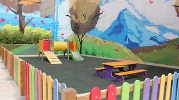 Un parque infantil con tobogán, estructuras de escalada y mesas de picnic.