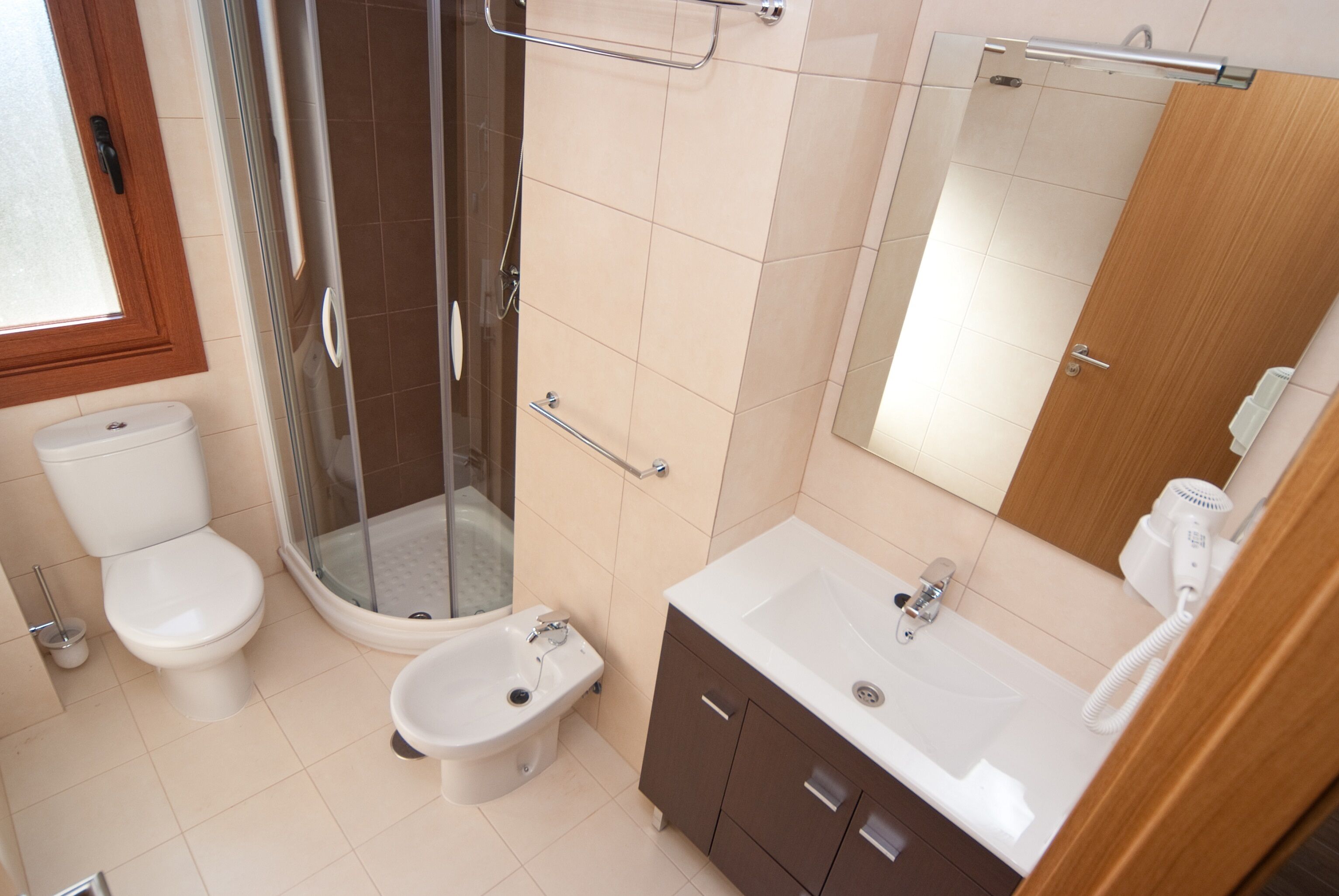 Et badeværelse med toilet, bidet, bruser og vask.