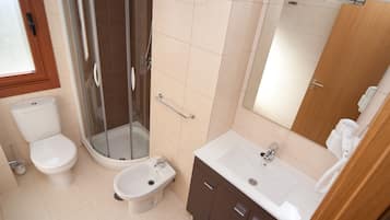 Et badeværelse med toilet, bidet, bruser og vask.