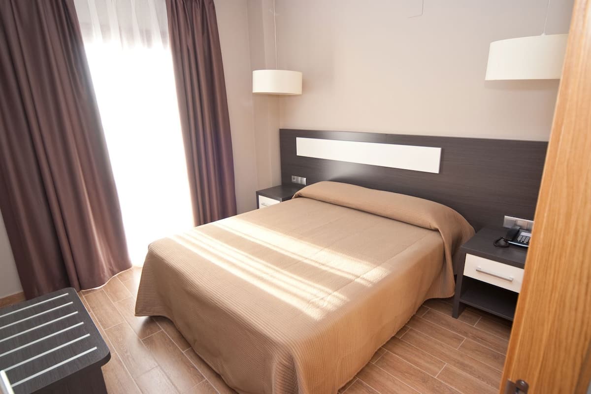 A hotel room with a bed, nightstands, a lamp, and a telephone.