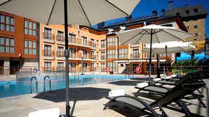 Area piscina di un hotel con lettini, ombrelloni e vista chiara sulla facciata dell'edificio.