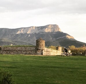 A grassy field with a stone wall and a small tower. - Apartahotel & Spa Jacetania (Jaca)