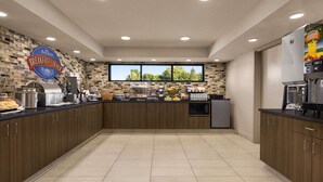 Une cuisine moderne dotée d’un bar pour prendre le petit-déjeuner, d’une machine à café et offrant une vue sur l’extérieur.