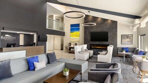 Un hall d’hôtel moderne comprenant un comptoir d’accueil, un espace salon et une cheminée.