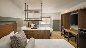 A modern hotel room with a bed, a desk, a television, and a window with a view of the outside. - River Canyon Lodge (Moab)