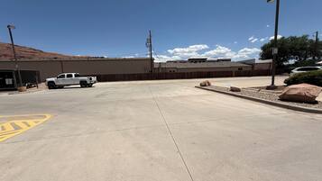A parking lot with a white truck parked near a building with a brown roof.