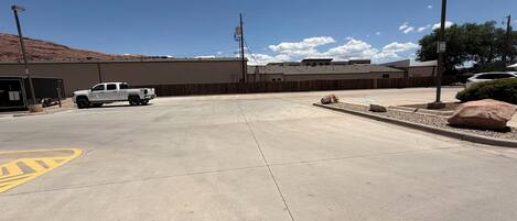 A parking lot with a white truck parked near a building with a brown roof.