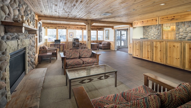A spacious living area with a stone fireplace, wooden furniture, and a large sofa. - River Canyon Lodge (Moab)