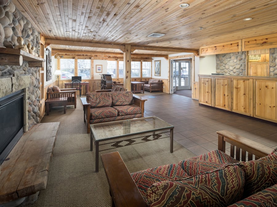 A spacious living area with a stone fireplace, wooden furniture, and a large sofa.