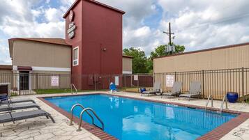 A swimming pool with lounge chairs and a red building with a sign.