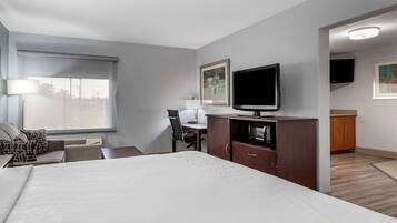 A hotel room with a large bed, a desk with a chair, a television, and artwork on the walls.