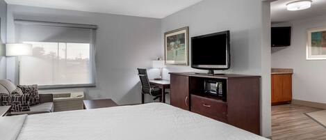 Habitación de hotel con una cama grande, un escritorio con silla, televisión y obras de arte en las paredes.