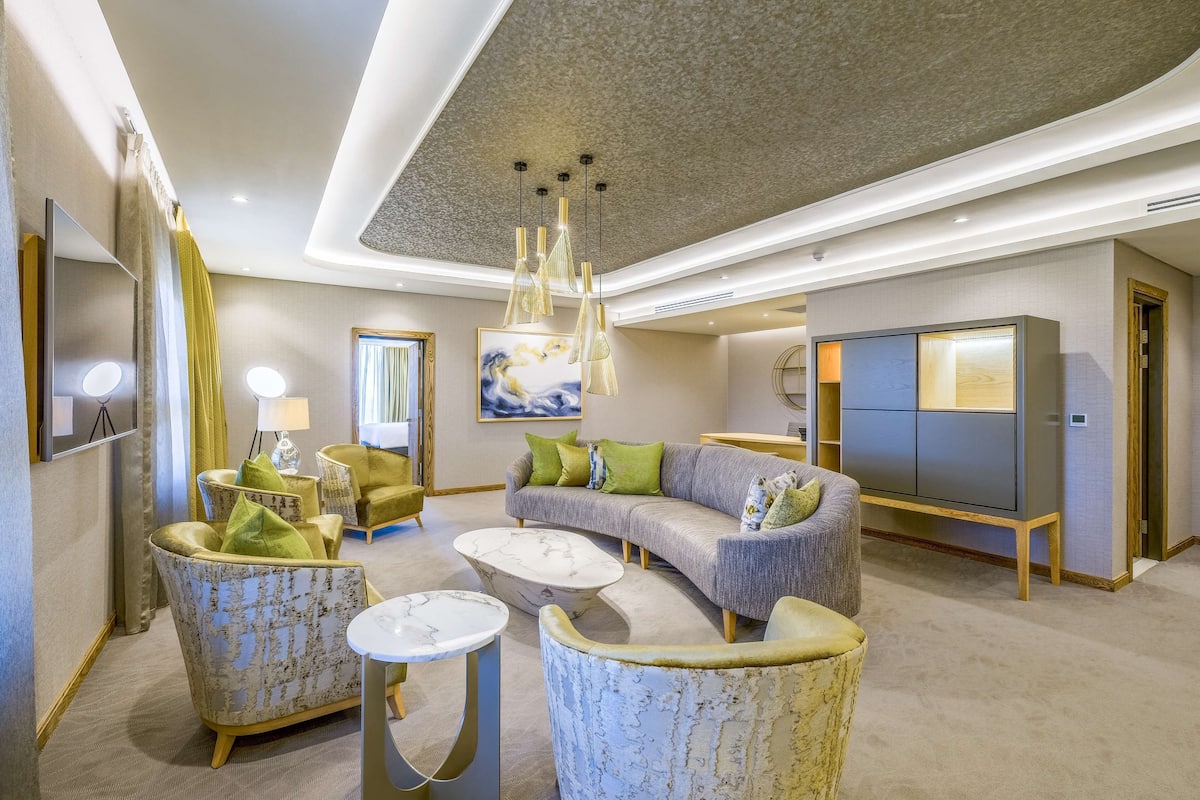 A modern living room with a sofa, armchairs, a coffee table, and a TV.