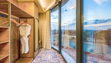 A hotel room with a large window, wooden wardrobe, and a patterned carpet.