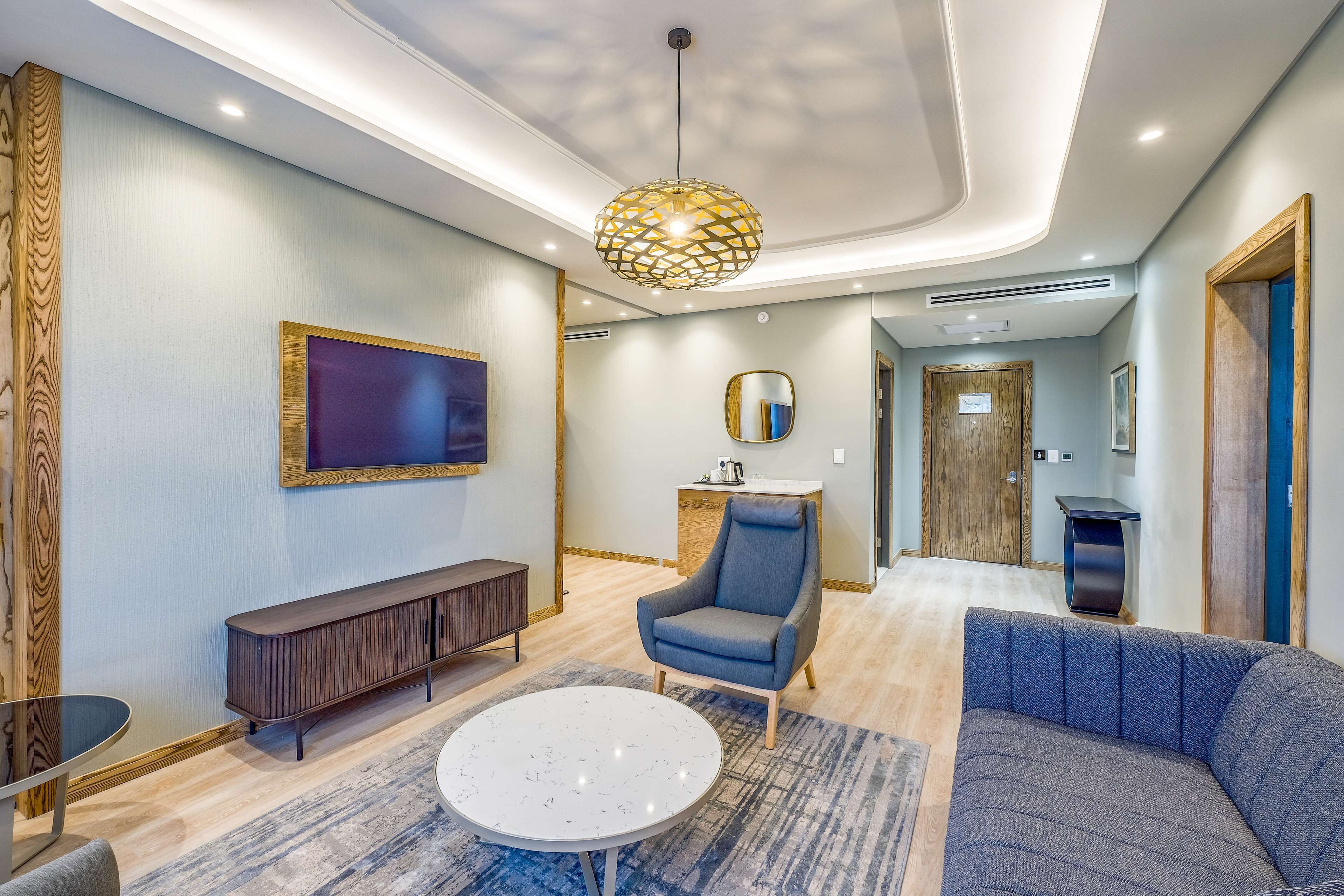 A modern living room with a sofa, armchair, and a round coffee table.