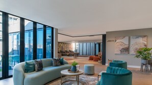 A modern living room with a sofa, teal armchairs, and a coffee table. - Radisson Hotel and Convention Centre OR Tambo Airport (Kempton Park)