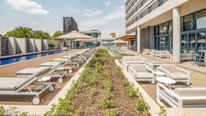 A rooftop pool area with lounge chairs, a small pool, and outdoor seating. - Radisson Hotel and Convention Centre OR Tambo Airport (Kempton Park)