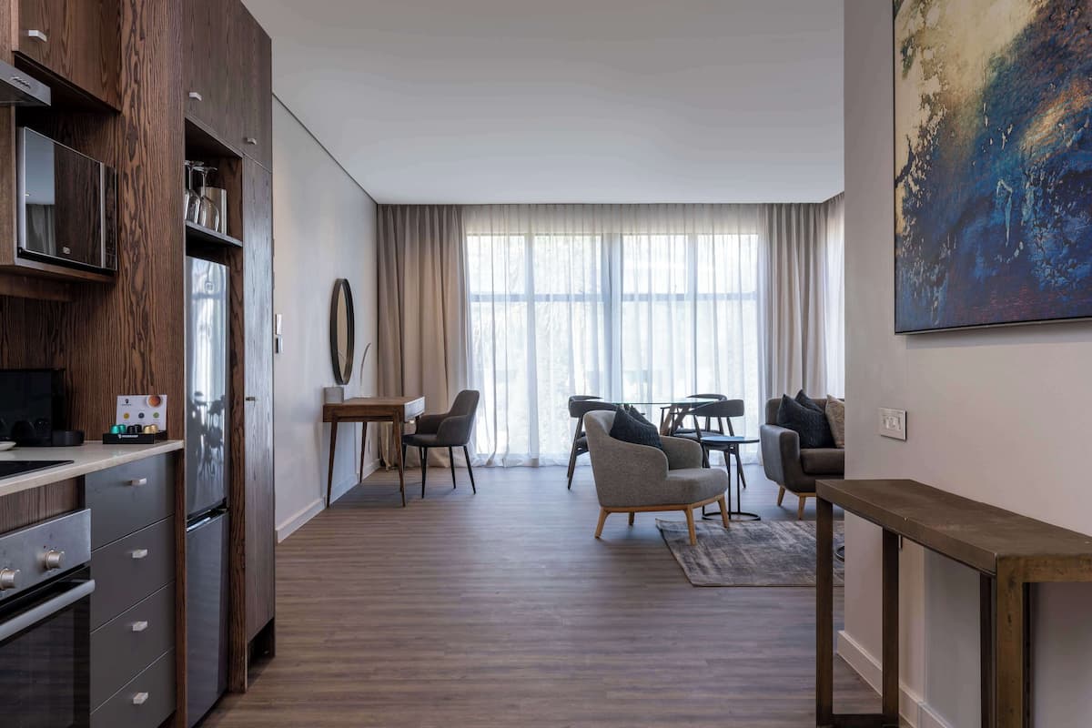 A modern living room with a dining area, wooden flooring, and a large abstract painting on the wall.