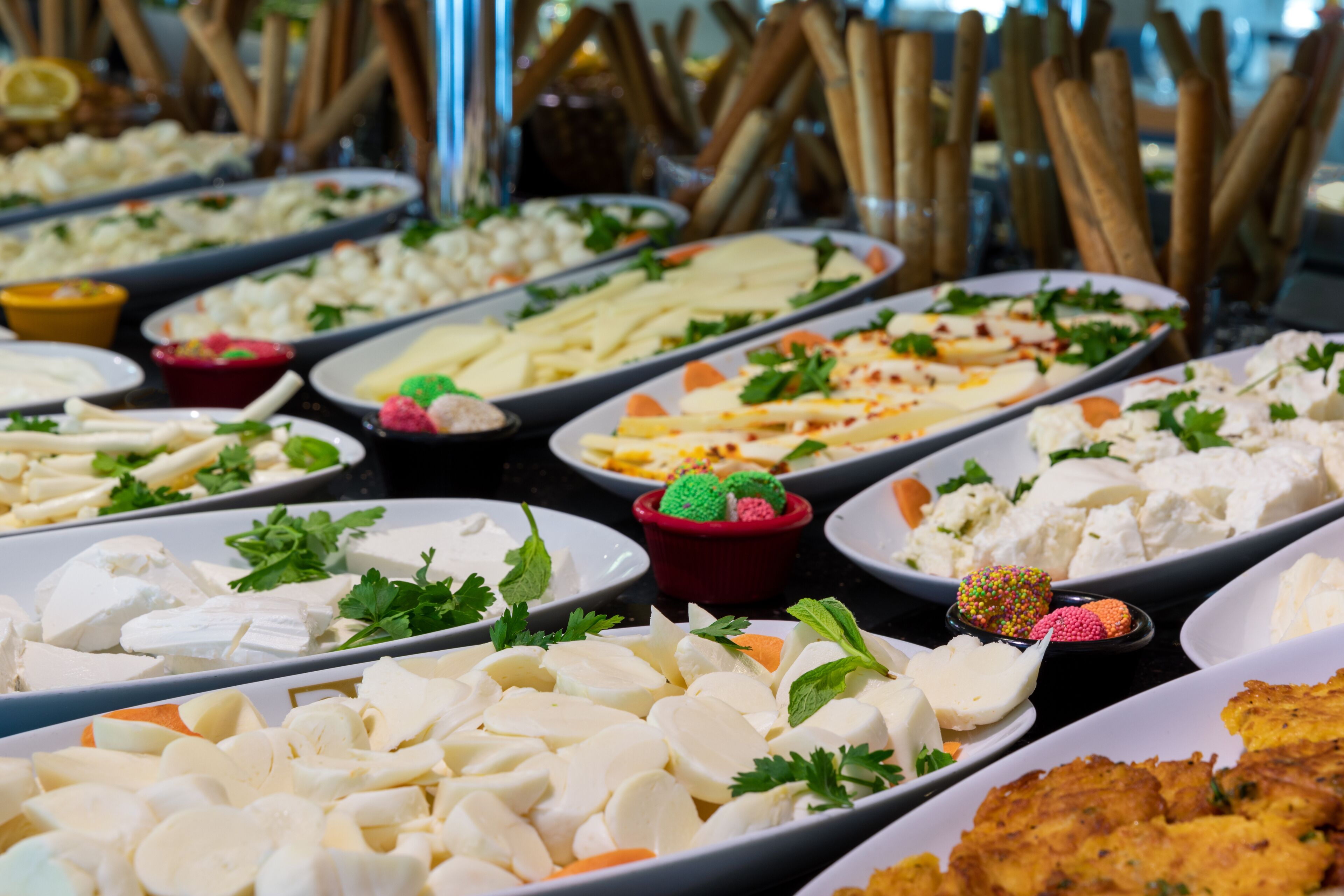 Un bufé con diversas opciones de comida, entre ellas queso, frutas y adornos.
