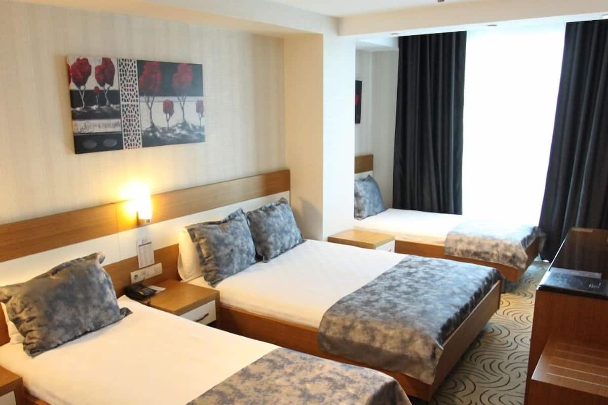 A hotel room with two beds, a desk, a chair, and a TV.