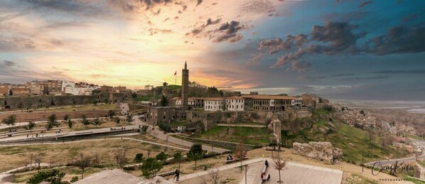 Un paisaje urbano histórico con una torre destacada, ruinas antiguas y una mezcla de edificios antiguos y modernos.