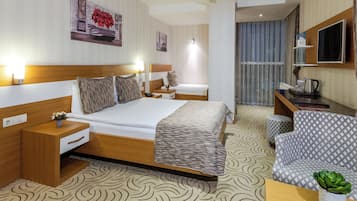 A hotel room with a bed, bedside tables, a desk, a chair, and a television.