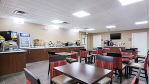 A restaurant with booths and tables, a kitchen area, and a TV mounted on the wall. - Comfort Inn Kings Mountain (Kings Mountain)