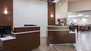 A reception area with two wooden reception desks, a stone wall, and a tiled floor. - Comfort Inn Kings Mountain (Kings Mountain)
