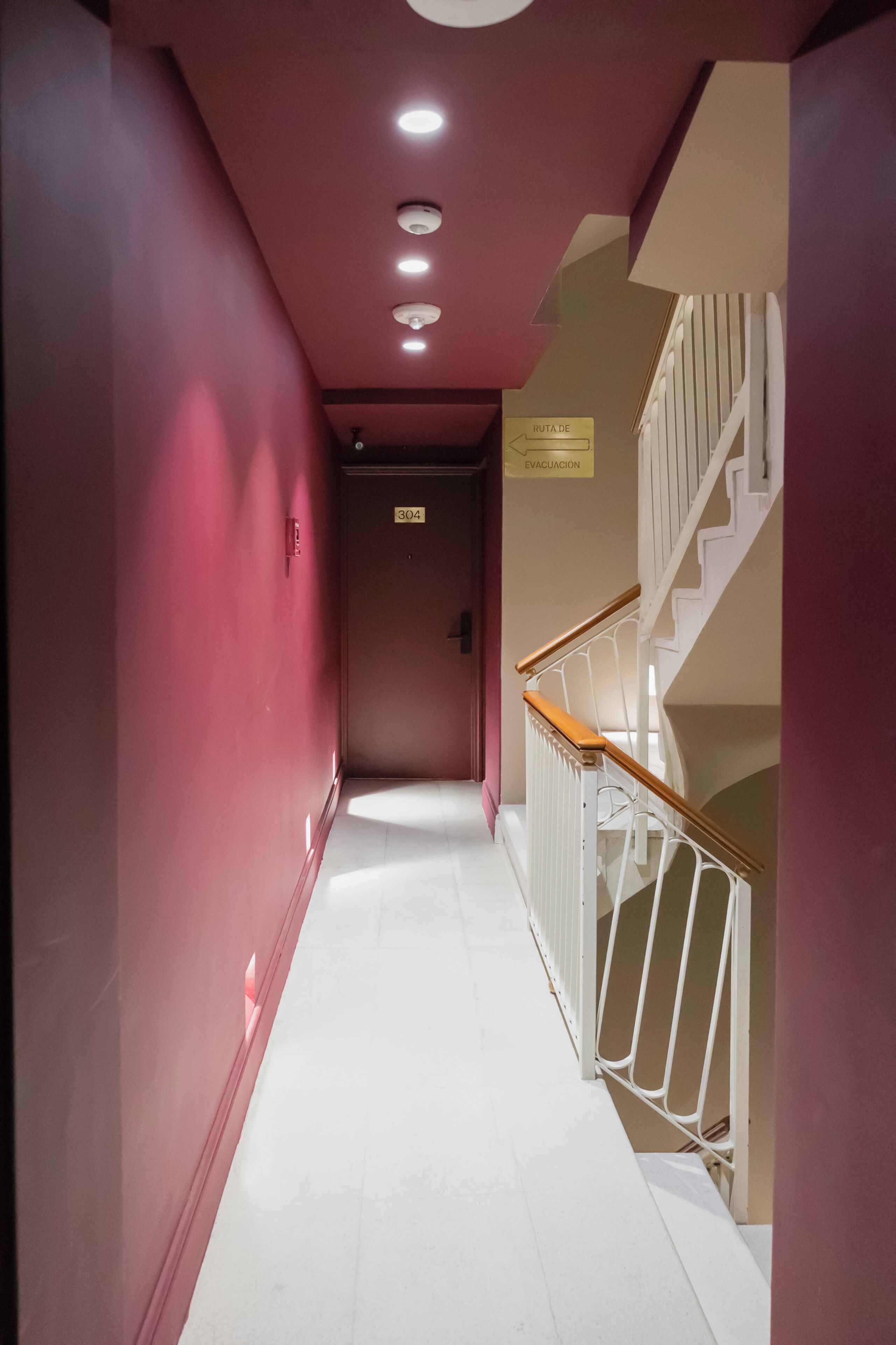 A hallway with a staircase, a sign indicating an evacuation route, and a door labeled '304'.
