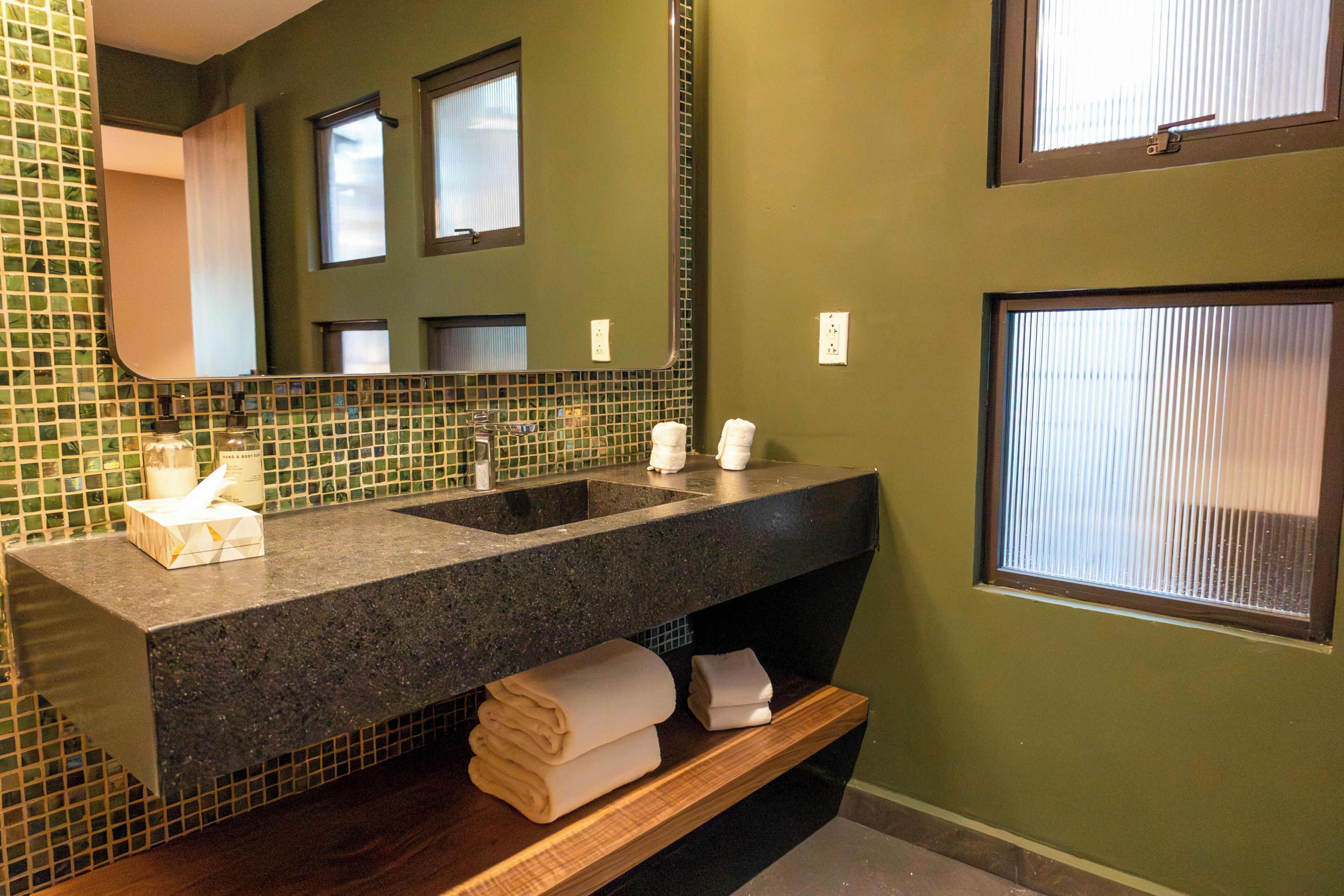 A bathroom with a large mirror, two sinks, and a towel rack.