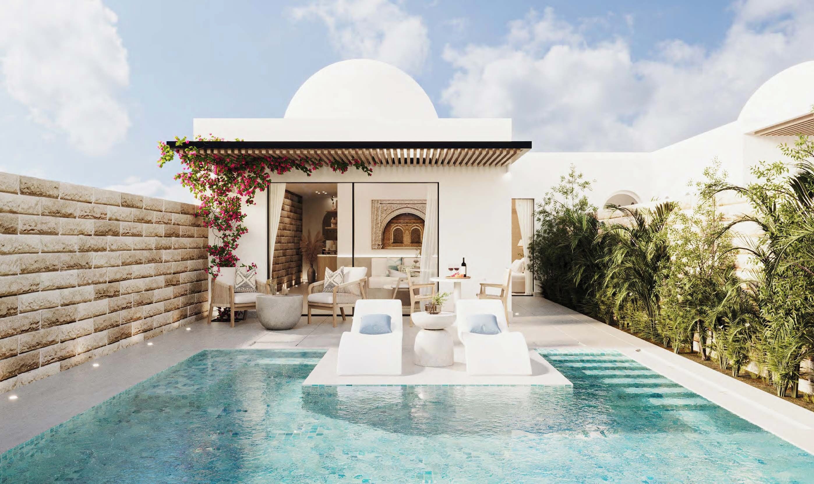 A poolside area with lounge chairs, a small seating area, and a view of a building with arches.