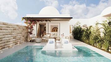 A poolside area with lounge chairs, a small seating area, and a view of a building with arches.