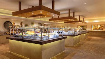 Un espace buffet doté de plusieurs présentoirs de nourriture, d’un sol à motifs et d’un plafond avec des poutres en bois et des luminaires encastrés.