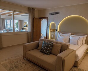 A hotel room with a bed, a sofa, a large window, and a view of the city. - Fort Arabesque Resort, Spa & Villas (Makadi Bay)