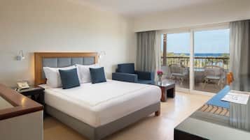 Habitación de hotel con una cama grande, un escritorio, una silla y un balcón con vistas.