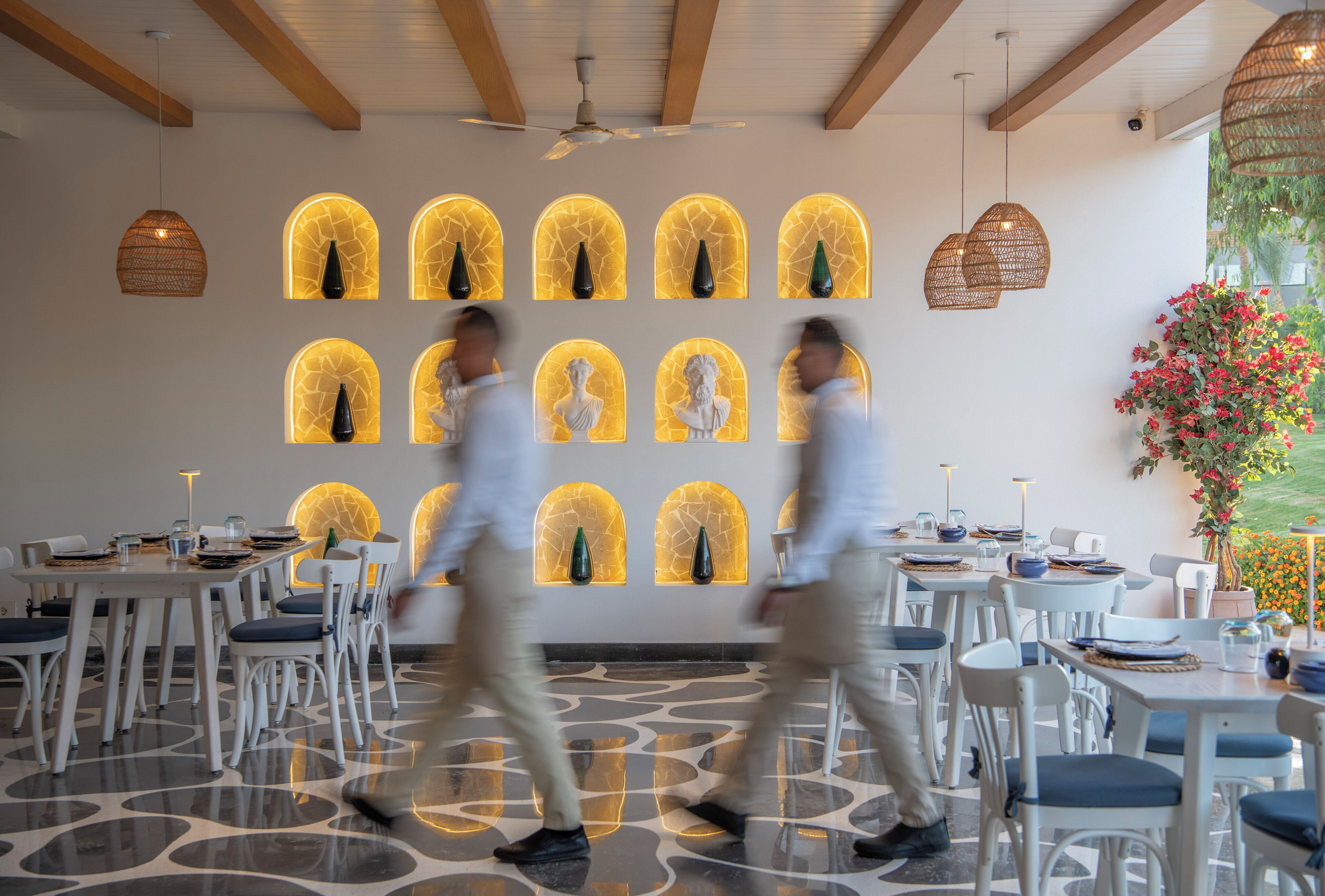 A restaurant interior with tables, chairs, and decorative wall sconces.