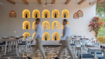 A restaurant interior with tables, chairs, and decorative wall sconces.
