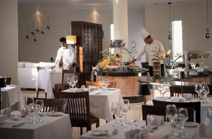 En restaurang med bord uppdukade för servering, ett område med buffé och en bar.
