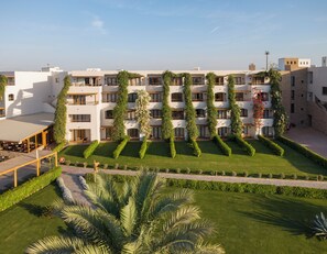 A multi-story hotel with a rooftop terrace and a well-manicured garden.