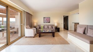 Un salon moderne comprenant un canapé, des fauteuils, une table basse et une table à manger agrémentée d’un vase de fleurs.