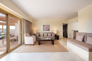 A modern living room with a sofa, armchairs, a coffee table, and a dining table set with a vase of flowers. - Fort Arabesque Resort, Spa & Villas (Makadi Bay)