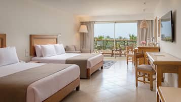 A hotel room with two beds, a desk, a chair, and a balcony with a view.