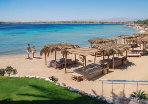 A beachside resort with thatched umbrellas, lounge chairs, and a clear view of the sea. - Fort Arabesque Resort, Spa & Villas (Makadi Bay)