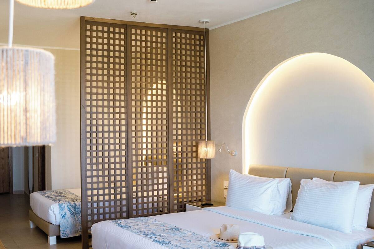 Ett modernt hotellrum med en stor säng, en vägg av trä och en rund vägglampa.