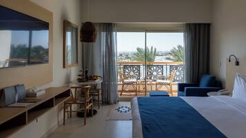 Habitación de hotel con cama, escritorio, silla, balcón con vistas y zona de comedor.
