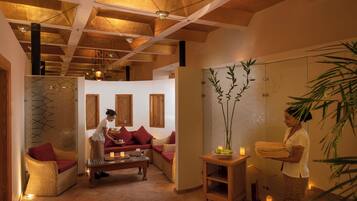 Een wellnessruimte met een houten plafond, een bank, een tafel met kaarsen en een wand met een geometrisch patroon.