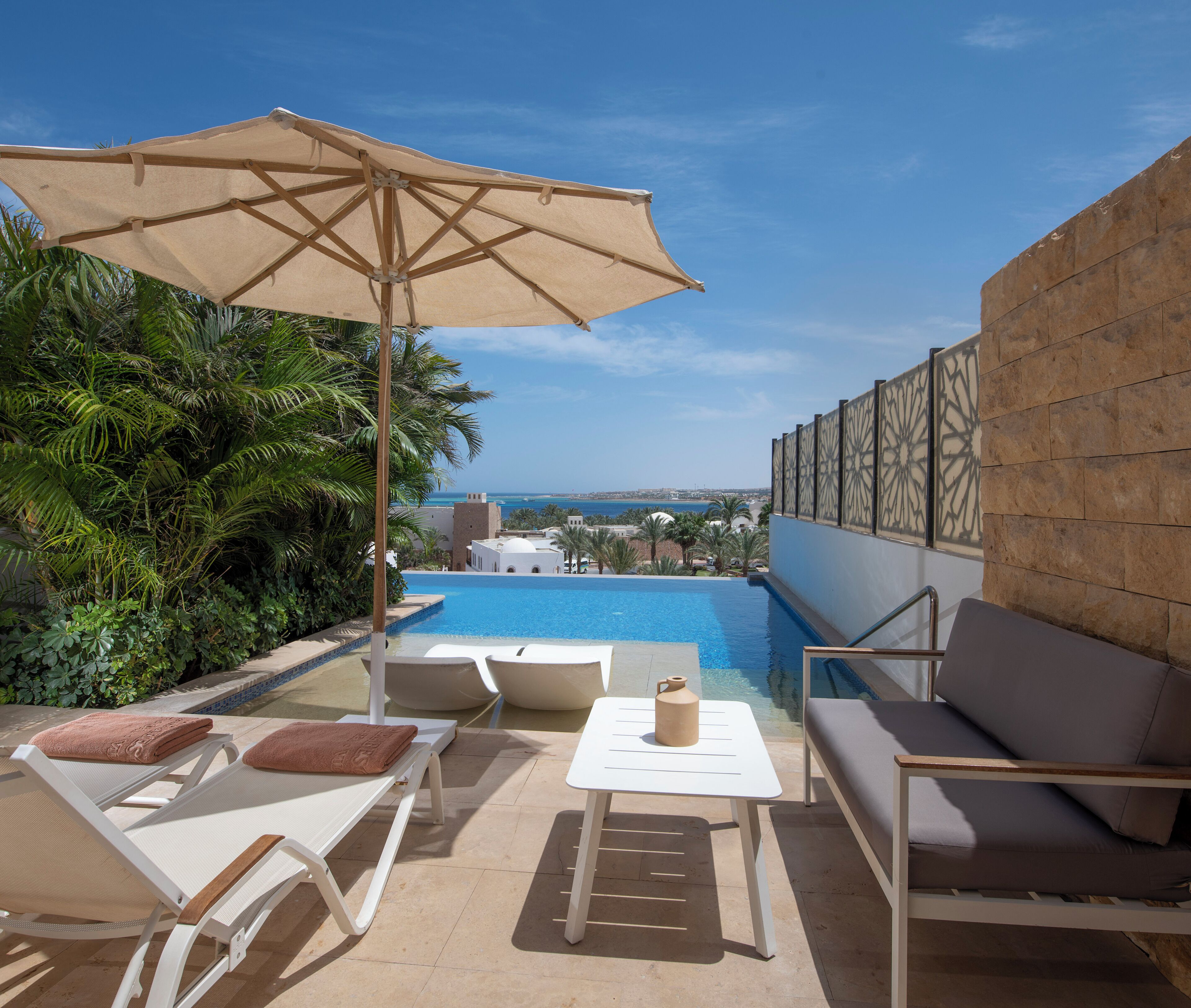 An outdoor pool area with lounge chairs, a table, and an umbrella.