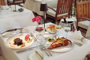A dining table set with plates of food, glasses of wine, and cutlery. - Fort Arabesque Resort, Spa & Villas (Makadi Bay)