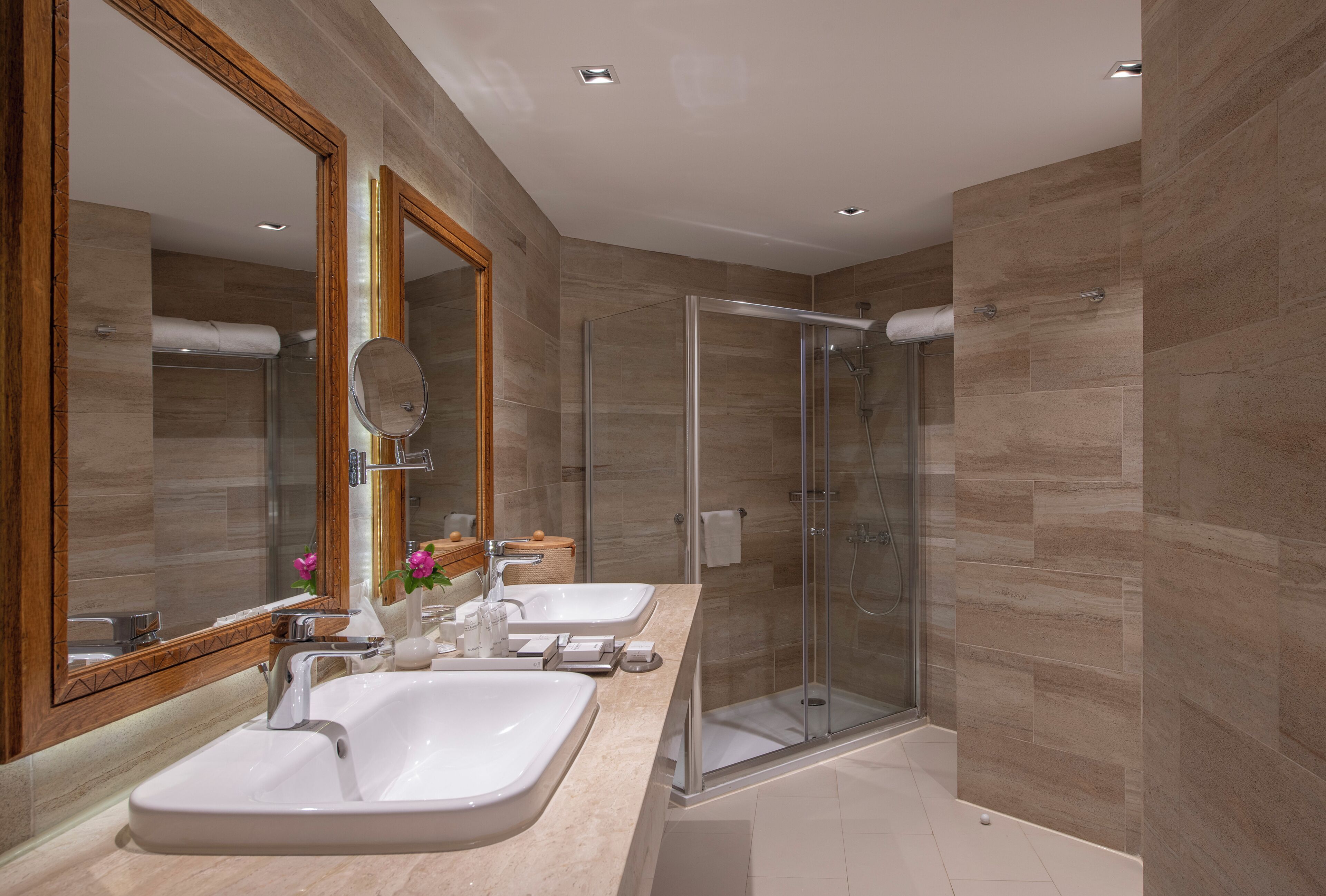 Une salle de bain moderne avec deux lavabos, une douche à l’italienne en verre et un grand miroir.